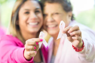 Mom and daughter wearing pink together, raising their pink ribbons