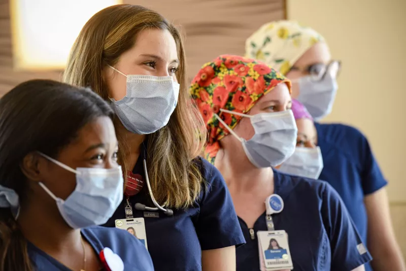 Four masked nurses smiling, diversity