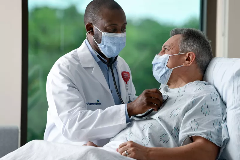 Masked doctor with masked patient in Emergency Room.