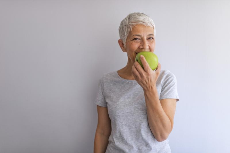 Woman eating an apple for her digestive health.