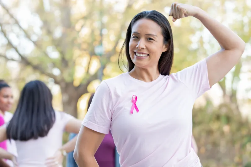 Woman wearing a pink shirt, flexing her muscles