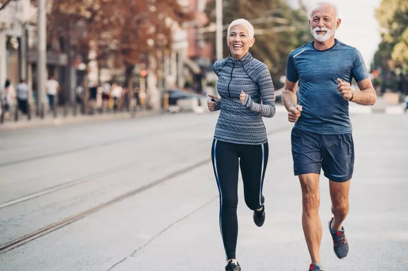 Older couple running together on the sidewalk