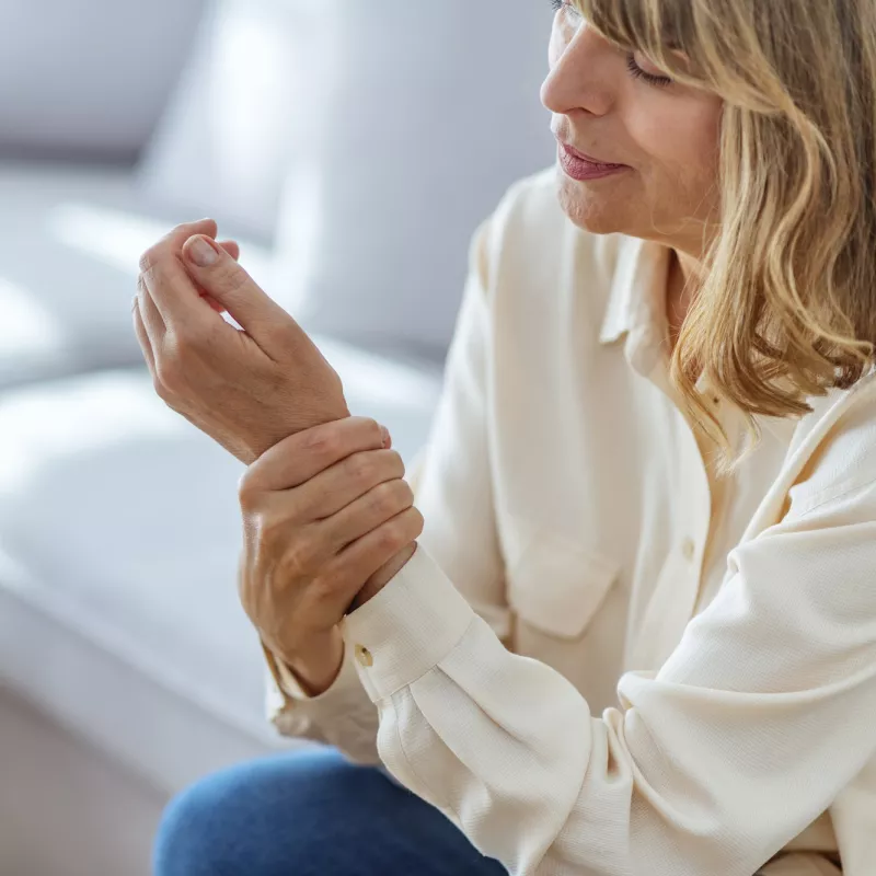 A woman with arthritis massages her hand.